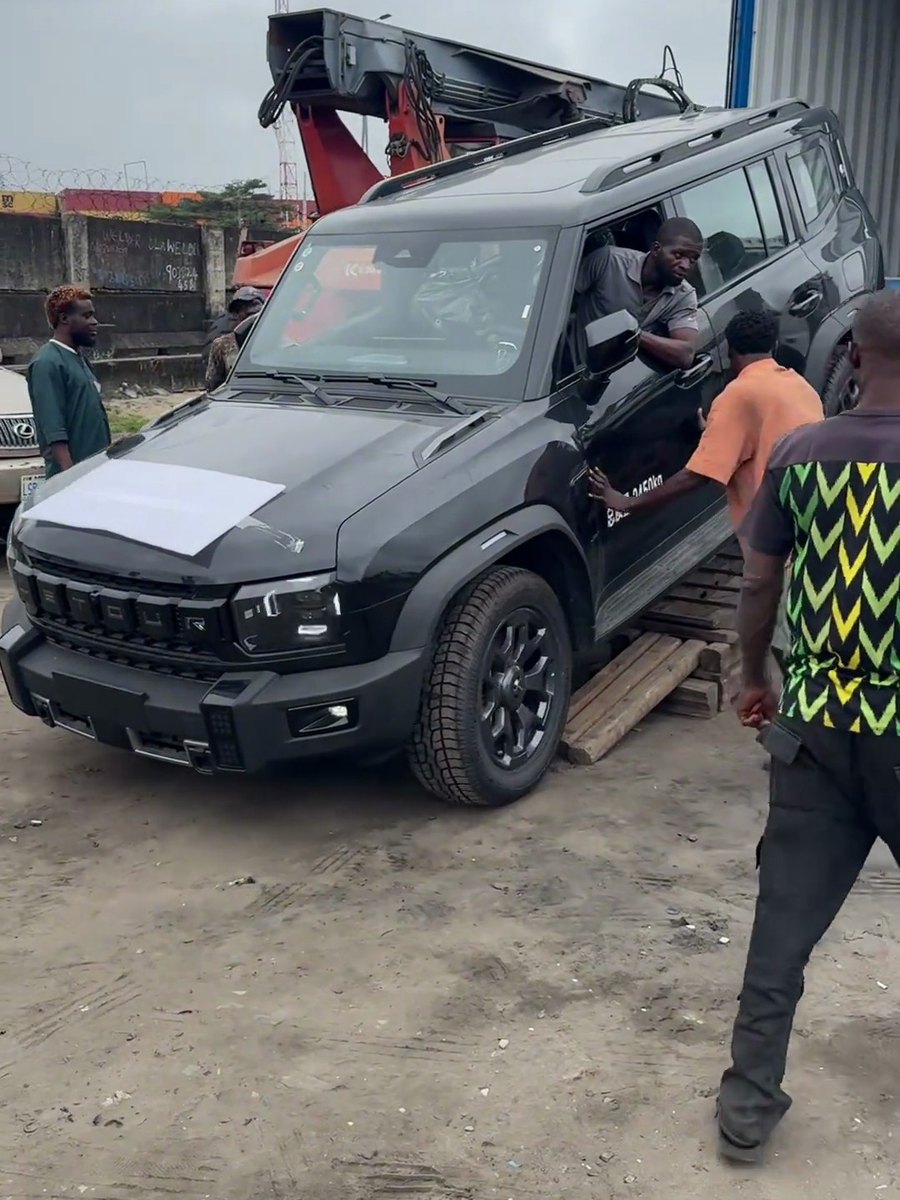 Driver at the wheel as an SUV is driven out of its container at a destination yard