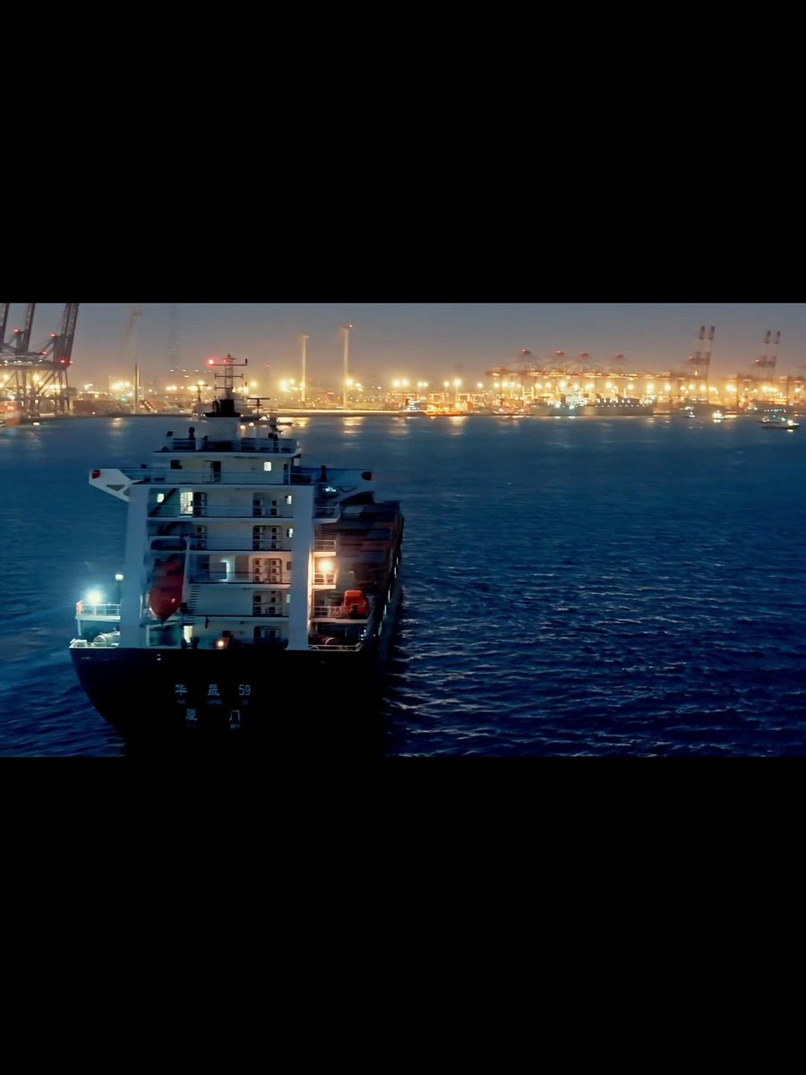 Wide night view of a working terminal with a vessel alongside and cranes lit up