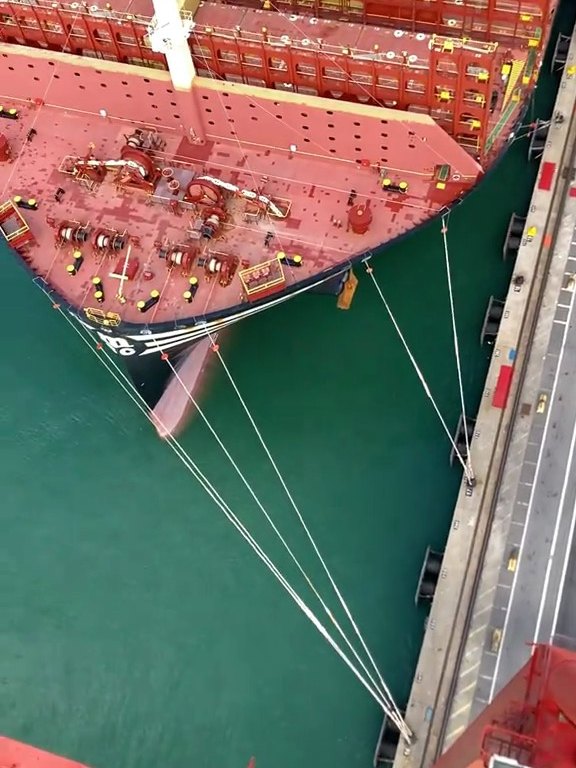 Aerial view of a large container vessel bow alongside the quay with mooring lines