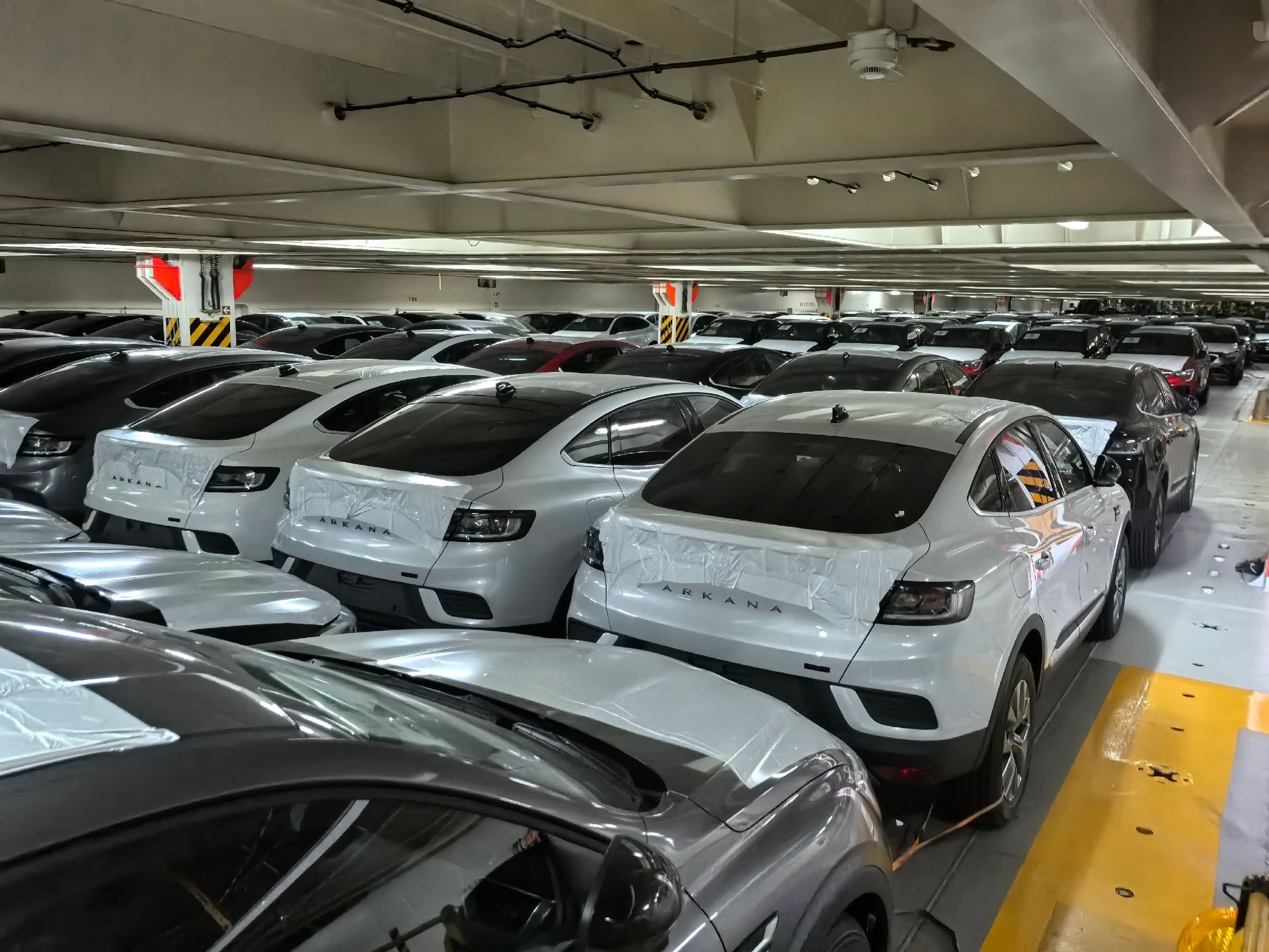 Passenger cars stowed in rows on the vehicle deck of a RoRo vessel with protective film