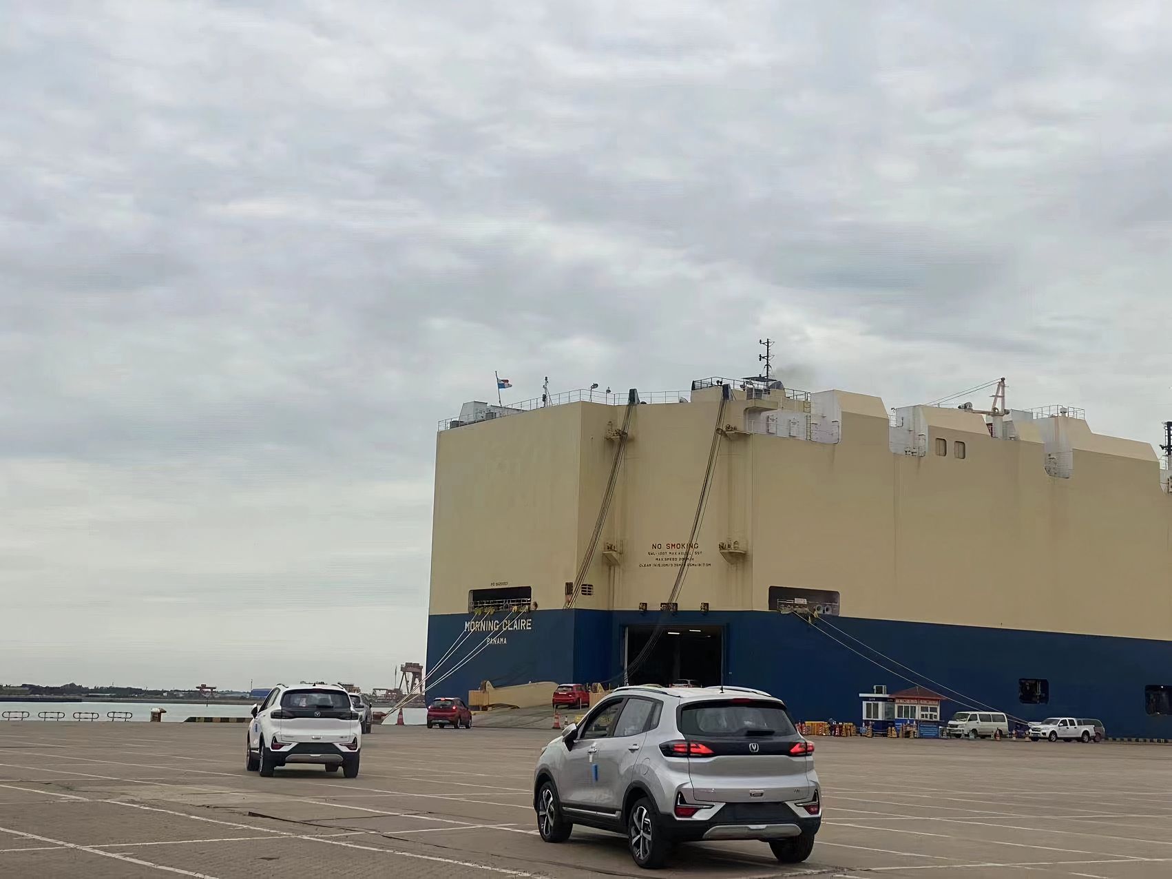 Vehicles driving across the quay toward the open stern ramp of a RoRo vessel