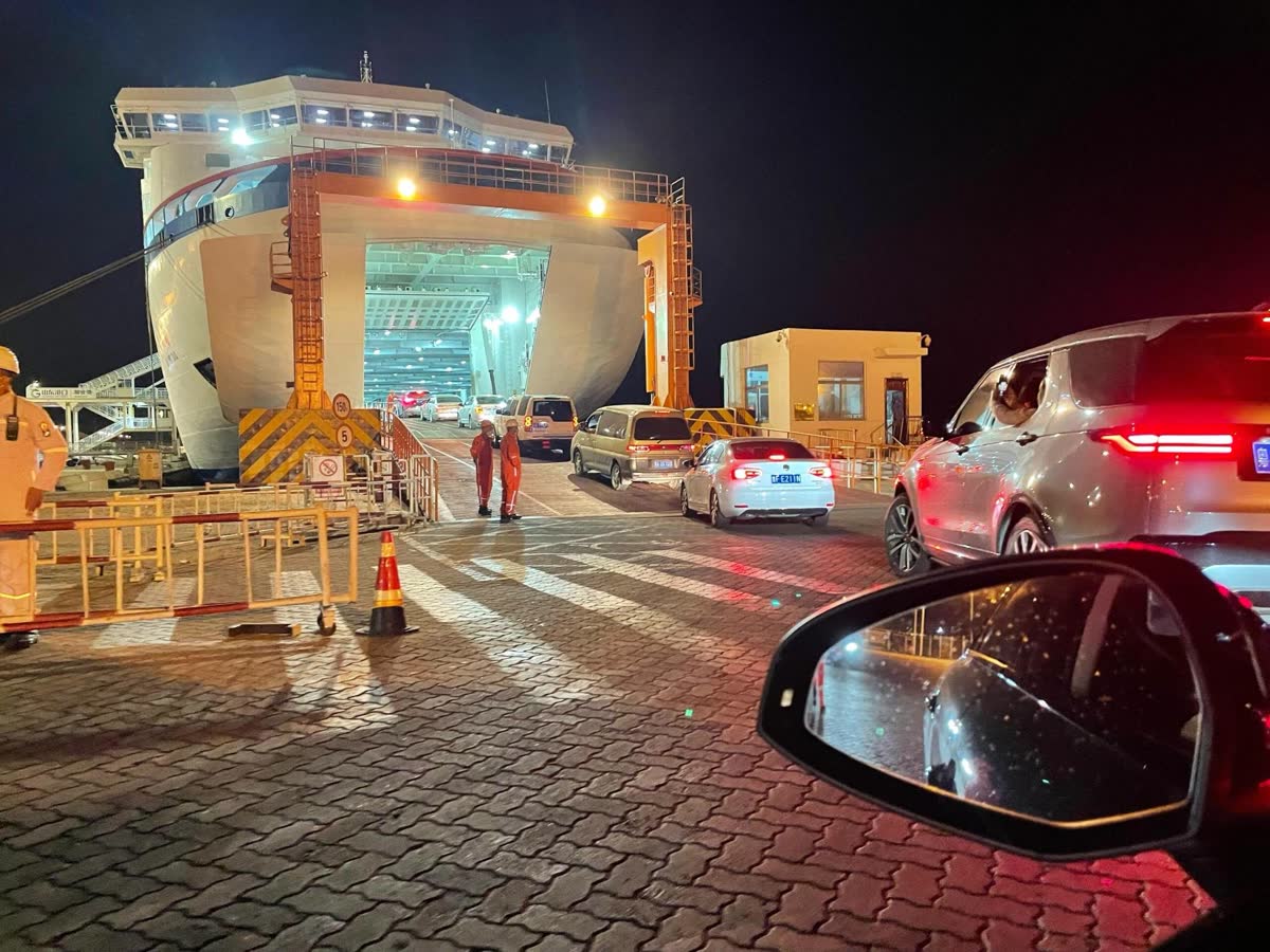 Vehicles queuing to board a RoRo vessel at night with the stern ramp lowered